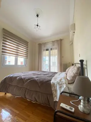 a bedroom with a bed and a table with a lamp at Elegant Apartment in Athens