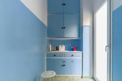 a blue room with a cabinet and a chair at Spacious 2BA next to the park and Archeological museum in Athens