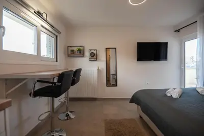 a bedroom with a bed and a desk and a tv at Studio with panoramic Athens view in Athens
