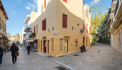 a street with a yellow building and people walking down the street at Plaka Apartment With Terrace View in Athens