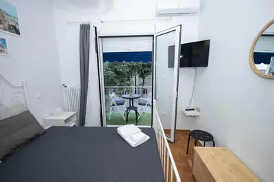 a room with a bed and a balcony with a table at ΑΙΘΡΑ Suite in Athens