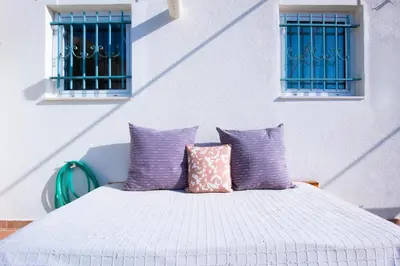 a white bed with purple pillows and two windows at Loft Apt with Acropolis View in Athens