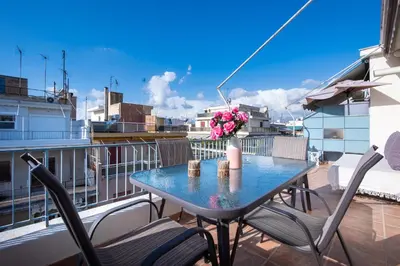 a table with chairs and a vase of flowers on a balcony at Loft Apt with Acropolis View in Athens