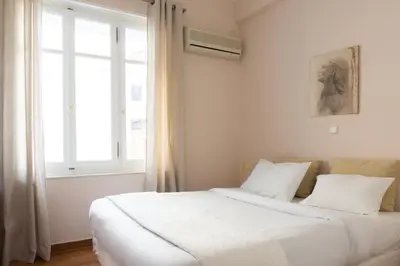 a bedroom with a bed with white sheets and a window at Hadrians Den in Heart of Plaka by JJ Hospitality in Athens