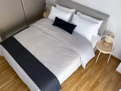 a large bed with white sheets and black pillows at Anneta’s home in Athens