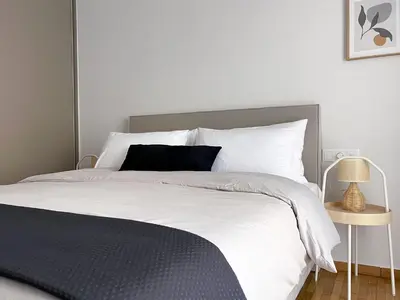 a bedroom with a large bed with white sheets and a lamp at Anneta’s home in Athens