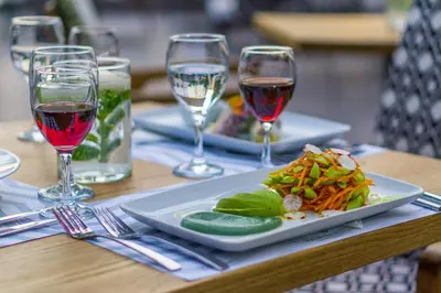 a plate of food on a table with glasses of wine at Palmyra Beach Hotel in Athens
