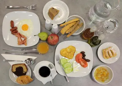 a table with plates of breakfast foods on it at Palmyra Beach Hotel in Athens