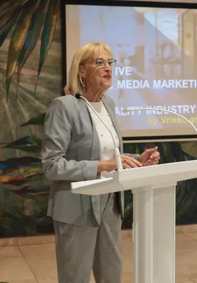 a woman standing at a podium with a microphone at Palmyra Beach Hotel in Athens