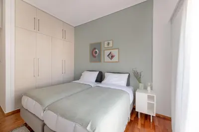 a white bedroom with a large bed with white cabinets at Foothills of Acropolis-Thissio 3 bdrm apartment in Athens