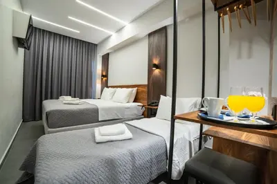 a hotel room with two beds and a tray of orange juice at Argo Hotel Piraeus in Piraeus