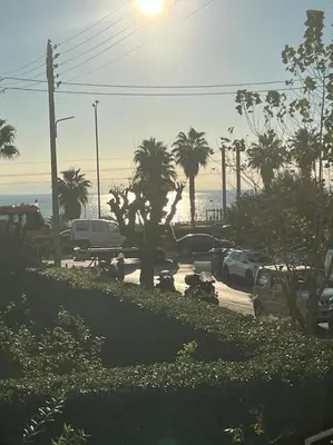 a parking lot with cars and palm trees and the ocean at Elegant Seaside 2 Floor Apartment in Athens