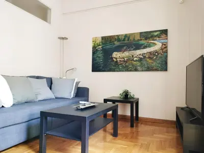 a living room with a blue couch and a table at Koukaki cozy apartment 5 minutes to metro in Athens