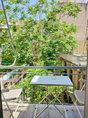 a table and chairs on a balcony with trees at Koukaki cozy apartment 5 minutes to metro in Athens