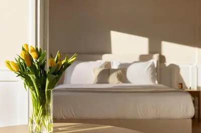 a vase of yellow flowers on a table with a bed at Meliti Apartment in Plaka in Athens