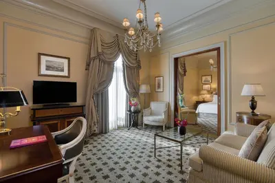 a living room with a couch and a television and a bed at Hotel Grande Bretagne, a Luxury Collection Hotel, Athens in Athens