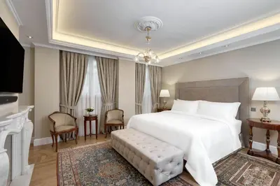 a bedroom with a large white bed and a fireplace at Hotel Grande Bretagne, a Luxury Collection Hotel, Athens in Athens