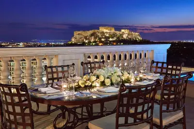a table with chairs and flowers on a balcony at Hotel Grande Bretagne, a Luxury Collection Hotel, Athens in Athens