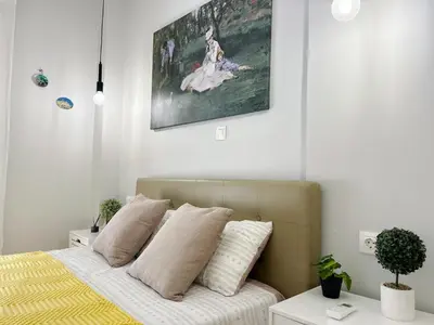 a bedroom with a bed with a painting on the wall at near Acropolis new 2 bedrooms apt in Koukaki in Athens