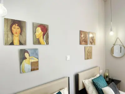 a bedroom with four paintings on the wall at near Acropolis new 2 bedrooms apt in Koukaki in Athens