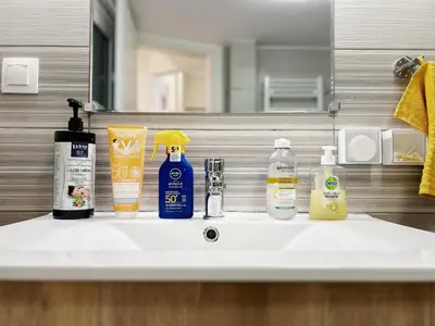 a bathroom sink with bottles of soap and a mirror at near Acropolis new 2 bedrooms apt in Koukaki in Athens
