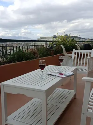 a white table with two glasses of wine on a balcony at Full Acropolis View Apartment in Athens