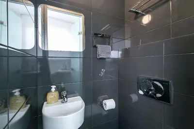 a black tiled bathroom with a sink and a mirror at Acropolis Panorama View Penthouse with Private Terraces A Contemporary Parthenon in Athens