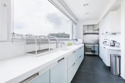 a kitchen with white cabinets and a large window at Acropolis Panorama View Penthouse with Private Terraces A Contemporary Parthenon in Athens