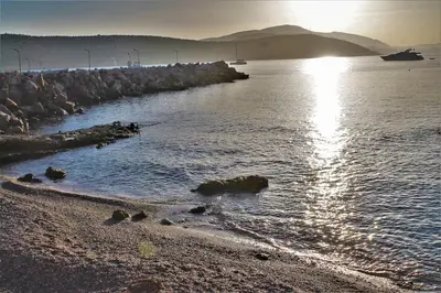 a beach with the sun reflecting on the water at Athens Riviera coast apartment in Athens