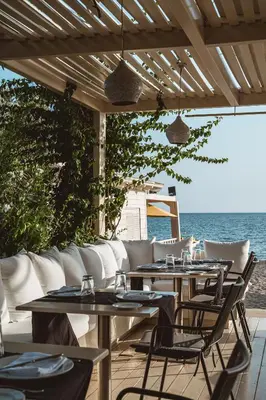 a patio with tables and chairs and the ocean at Plaza Resort in Anavissos
