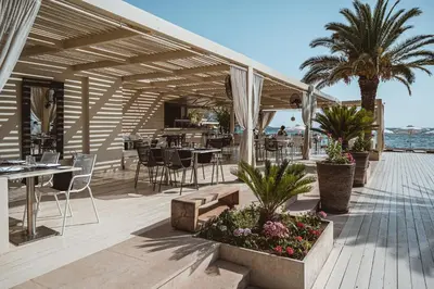 a patio with tables and chairs on the beach at Plaza Resort in Anavissos