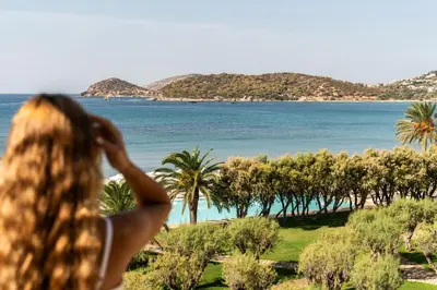 a woman looking out at the ocean and palm trees at Plaza Resort in Anavissos