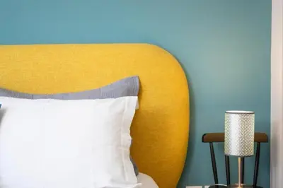 a bed with a yellow headboard and a blue wall at Crown Syntagma Apartment in Athens