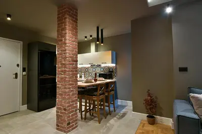 a kitchen with a brick pillar and a table with chairs at NewVintage Apartment in Athens