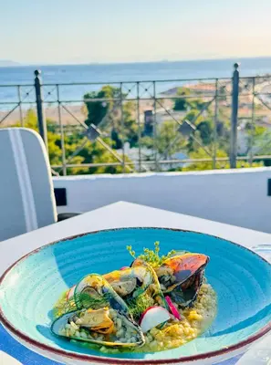 a plate of food on a table with a view of the ocean at Hotel London in Athens