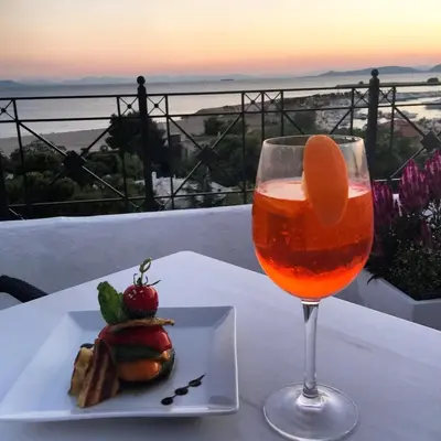 a plate of food and a glass of wine on a table at Hotel London in Athens