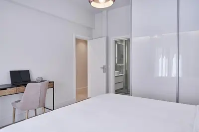 a white bedroom with a bed and a desk with a computer at Urban Heights 3BD Apt, next to Hilton in Athens
