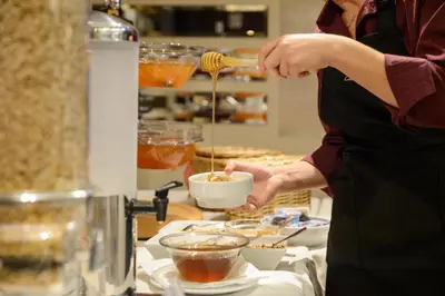 a woman is preparing food in a kitchen at The Athenian Callirhoe in Athens
