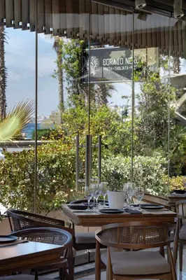a restaurant with tables and chairs in front of a window at Coral Hotel Athens in Athens