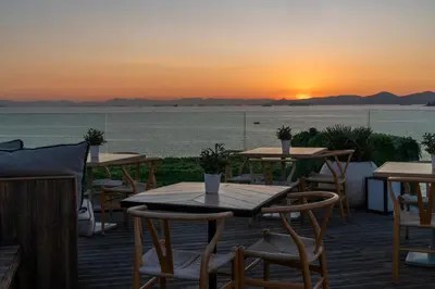 a view of the sunset from a restaurant with tables and chairs at Coral Hotel Athens in Athens