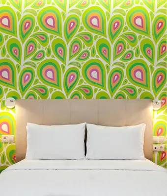 a bedroom with a green and pink patterned wall at Amazon Hotel in Athens