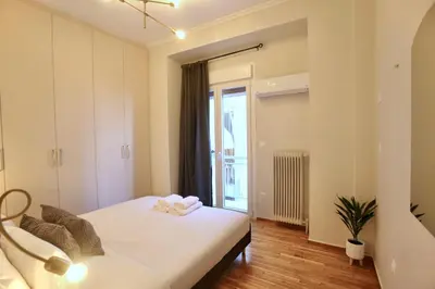 a bedroom with a white bed and a window at Cosy Nektariou in Athens
