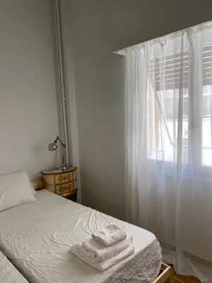 a bedroom with a bed with white sheets and a window at Graffiti Ground Floor in Athens