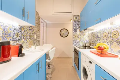 a kitchen with blue cabinets and a washing machine at Heart of Koukaki flat, 10’ walk to Acropolis in Athens