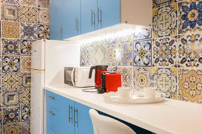 a kitchen with blue cabinets and blue and white tiles at Heart of Koukaki flat, 10’ walk to Acropolis in Athens