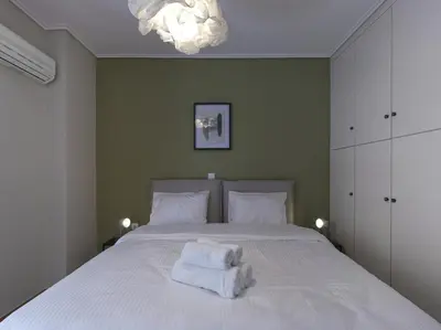 a bedroom with a bed with white sheets and a chandelier at 2 bedroom apartment close to children's hospital in Athens