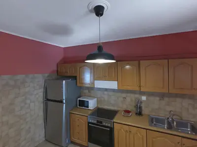 a kitchen with wooden cabinets and a stainless steel refrigerator at 2 bedroom apartment close to children's hospital in Athens