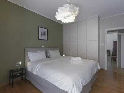 a bedroom with a large white bed with a chandelier at 2 bedroom apartment close to children's hospital in Athens