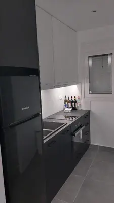 a kitchen with a black refrigerator and white cabinets at Cozy Nest in Athens