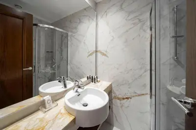 a white bathroom with a sink and a shower at Electra Palace Athens in Athens
